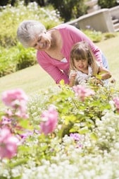 Grandmother and granddaughter outdoors in garden smiling